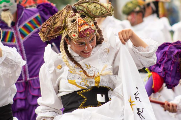 Mujer danzando feliz vestida de blanco en berbena callejera