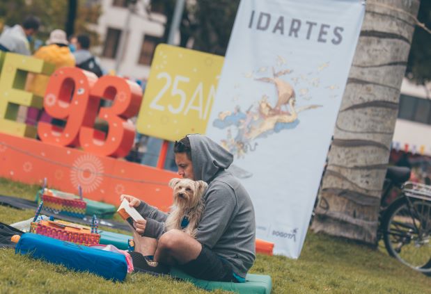 Hombre joven leyendo en un parque con su mascota